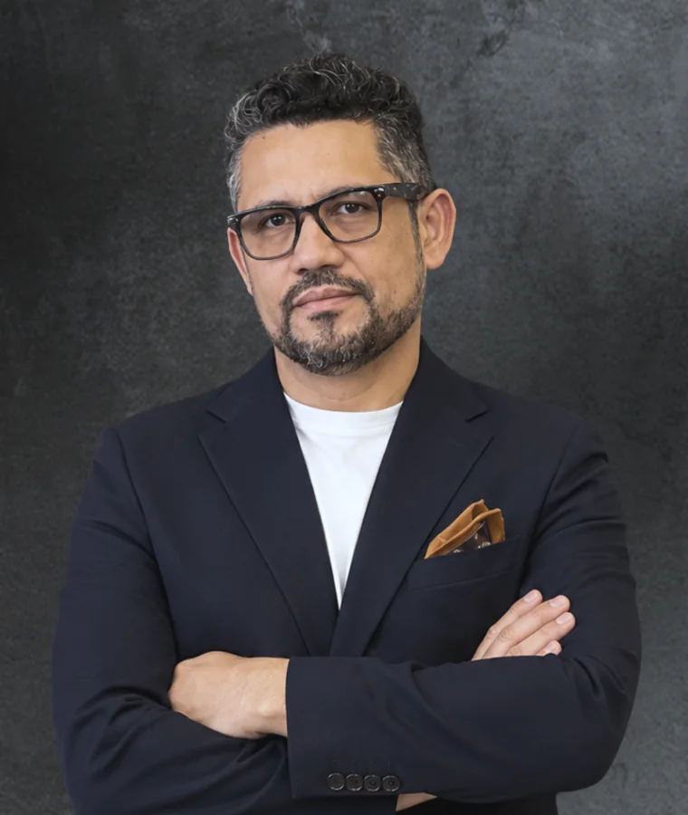 Retrato de Vagner Campos: blazer azul-marinho, camiseta branca, braços cruzados, olhar direto para a câmera.