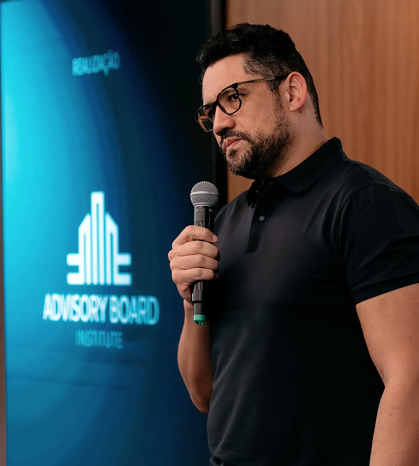 Vagner Campos ao microfone ao lado do logotipo do Advisory Board Institute