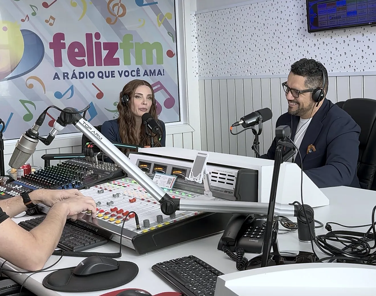 Vagner Campos de fones, ao microfone, durante programa no estúdio da Feliz FM