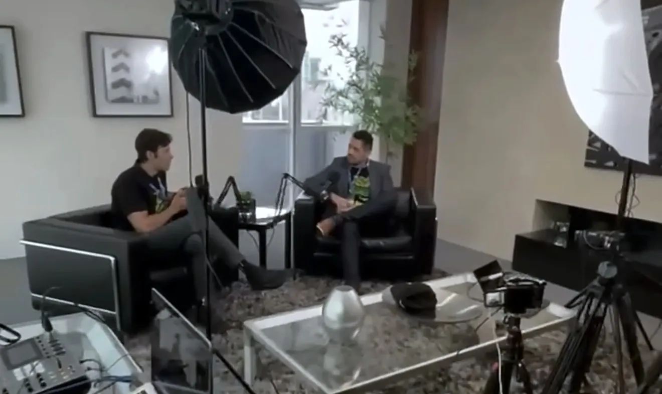 Vagner Campos sentado em uma poltrona, ao microfone, durante gravação do podcast AI Brasil, com iluminação de estúdio