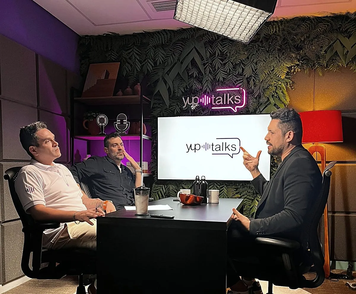 Vagner Campos gesticulando durante gravação do podcast Yup Talks, com dois apresentadores à mesa