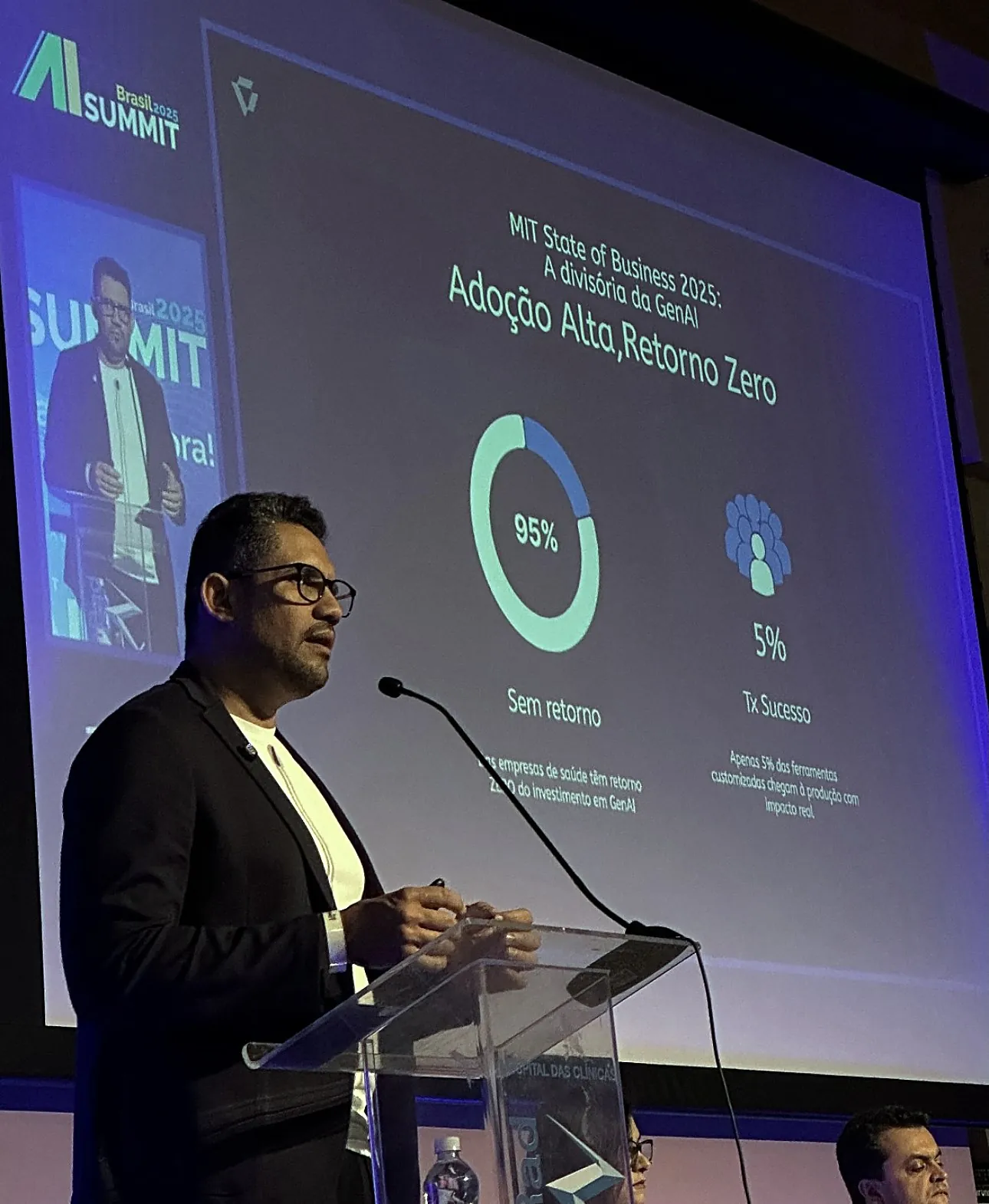 Vagner Campos ao púlpito do AI Summit Brasil 2025, com o slide Adoção alta, retorno zero ao fundo