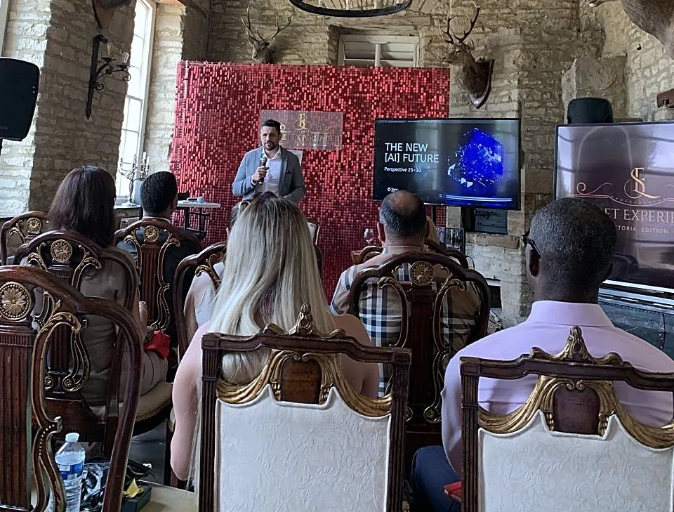 Vagner Campos palestrando para empresários sentados em um salão de pedra, com o slide The New AI Future ao lado